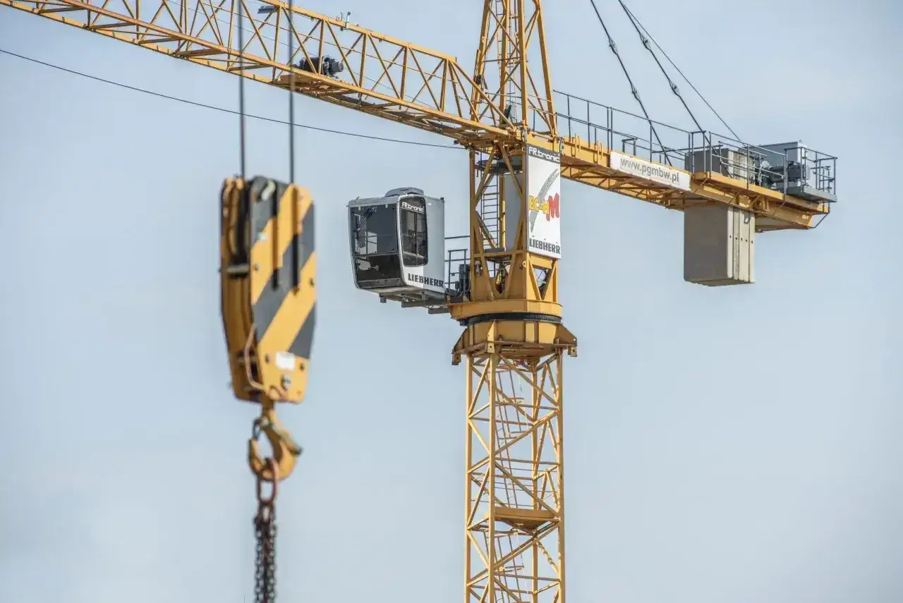 Żuraw budowlany z kabiną operatora. Zastanawiasz się, ile zarabia operator żurawia? To praca wymagająca odpowiedzialności.