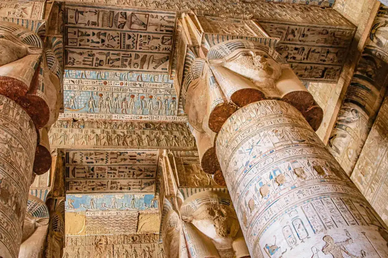 Columnas y techos de un templo egipcio cubiertos de jeroglíficos y relieves, incluyendo el famoso zodiaco de Dendera.
