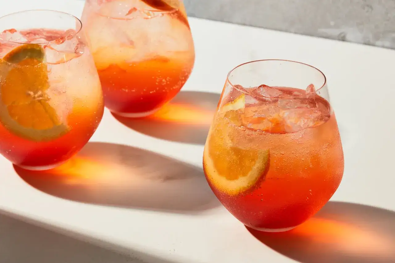 Trzy orzeźwiające drinki Aperol Spritz z plasterkami pomarańczy i lodem. Idealne na lato, z zawartością alkoholu 11%.