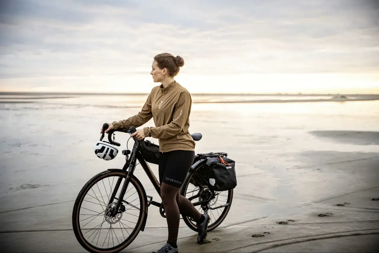 Frau mit Fahrrad am Strand, bereit für einen Abenteuer-Test. Der Diamant Nhoma Test ist bestanden, die Ausrüstung ist perfekt.