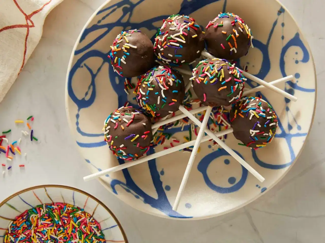Chokladbollar med strössel på en blåvit tallrik. Perfekt för ett enkelt cake pops recept.