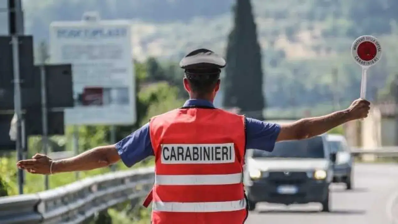 Un carabiniere con giubbotto catarifrangente e cappello dirige il traffico, segnalando con un disco 