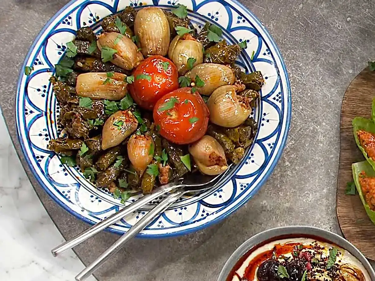 En vacker tallrik med fyllda vinblad, l&ouml;k och tomater. Ett perfekt dolma recept f&ouml;r en festm&aring;ltid.