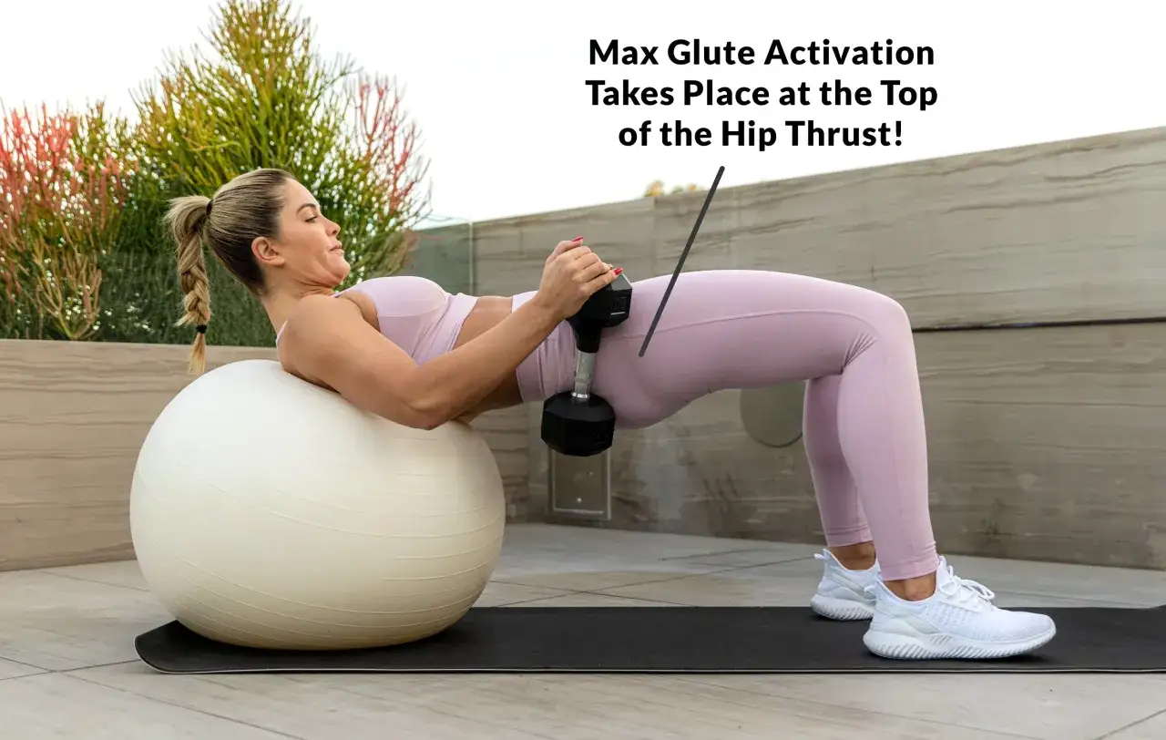 Kobieta wykonuje ćwiczenie hip thrust w domu, opierając się plecami o piłkę gimnastyczną i trzymając hantle.