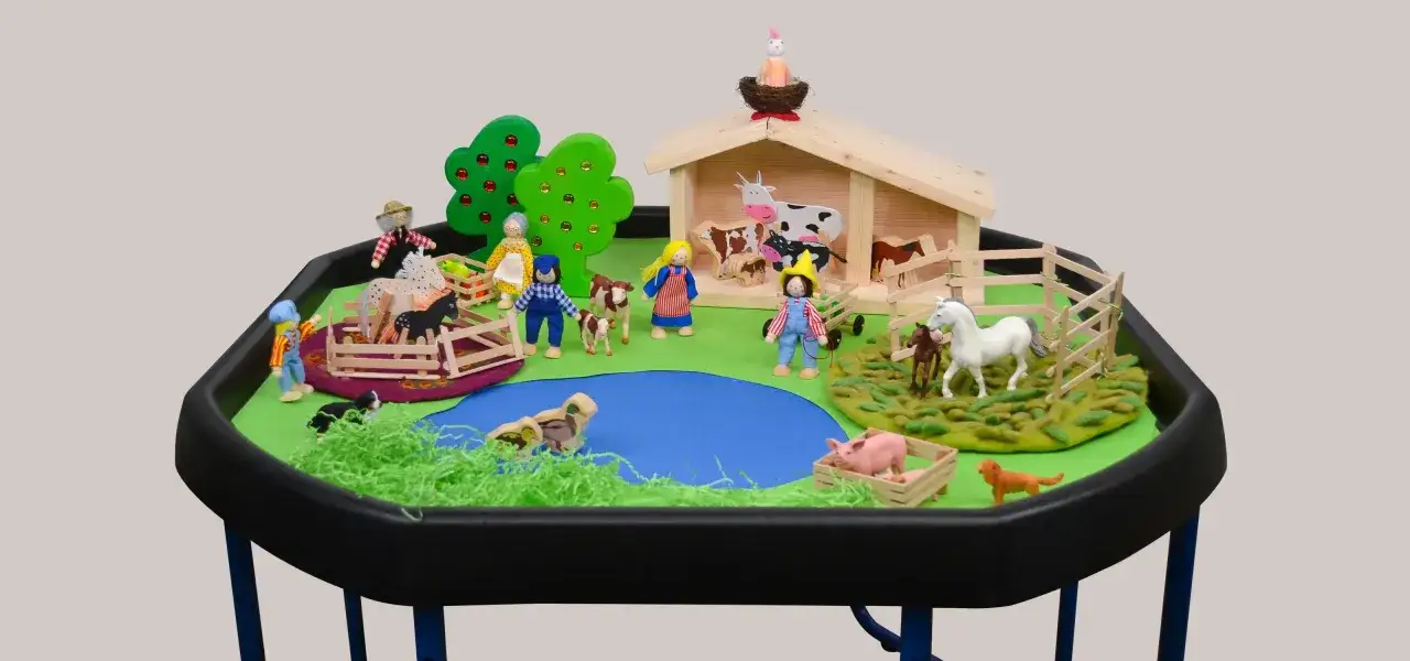Morgenkreis Thema Bauernhof: Kinder spielen mit Figuren auf einem Bauernhof mit Stall, Tieren und Teich.