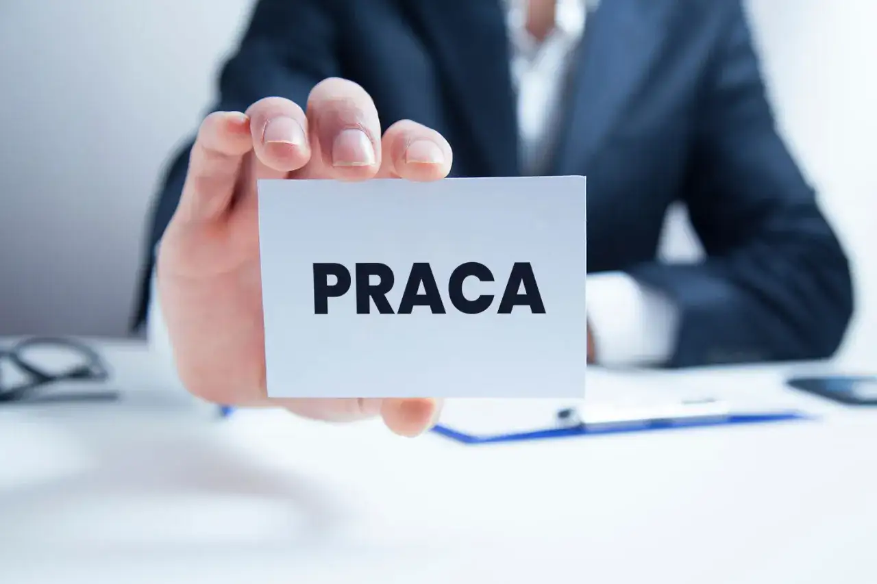 Mężczyzna w garniturze trzyma kartkę z napisem 