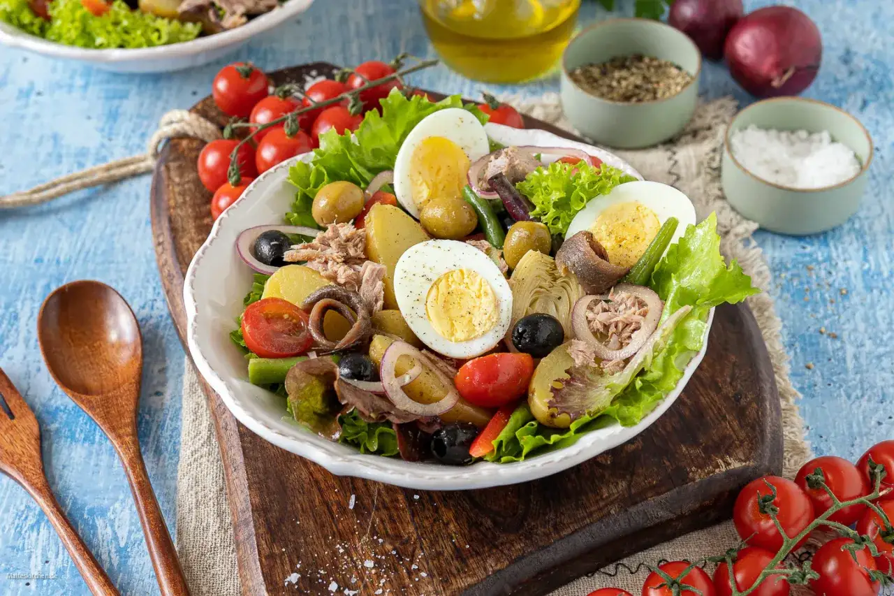 Ein bunter Nizza Salat mit Thunfisch, Ei, Kartoffeln, Oliven, Sardellen und Artischockenherzen.