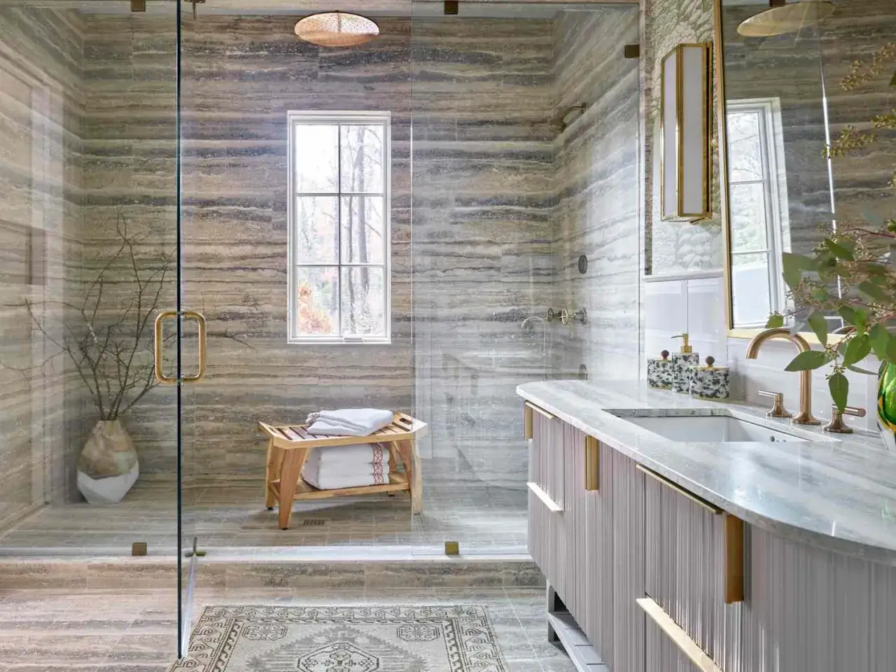 A luxurious new shower install features a glass enclosure with horizontal wood-look tile and a wooden bench.