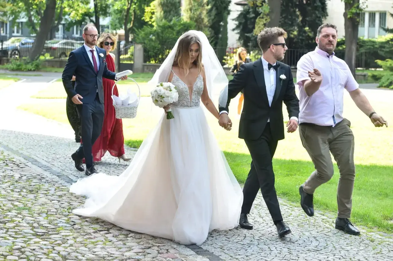 Antek Królikowski i Joanna Opozda idą razem do ślubu, ona w pięknej sukni, on w eleganckim garniturze.