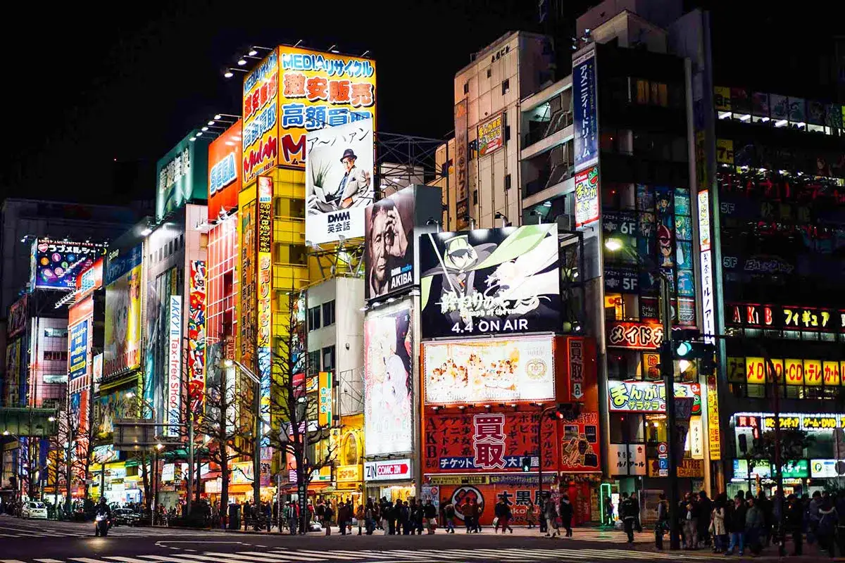 Tętniące życiem centrum Tokio nocą, rozświetlone neonami i wielkimi billboardami reklamowymi.