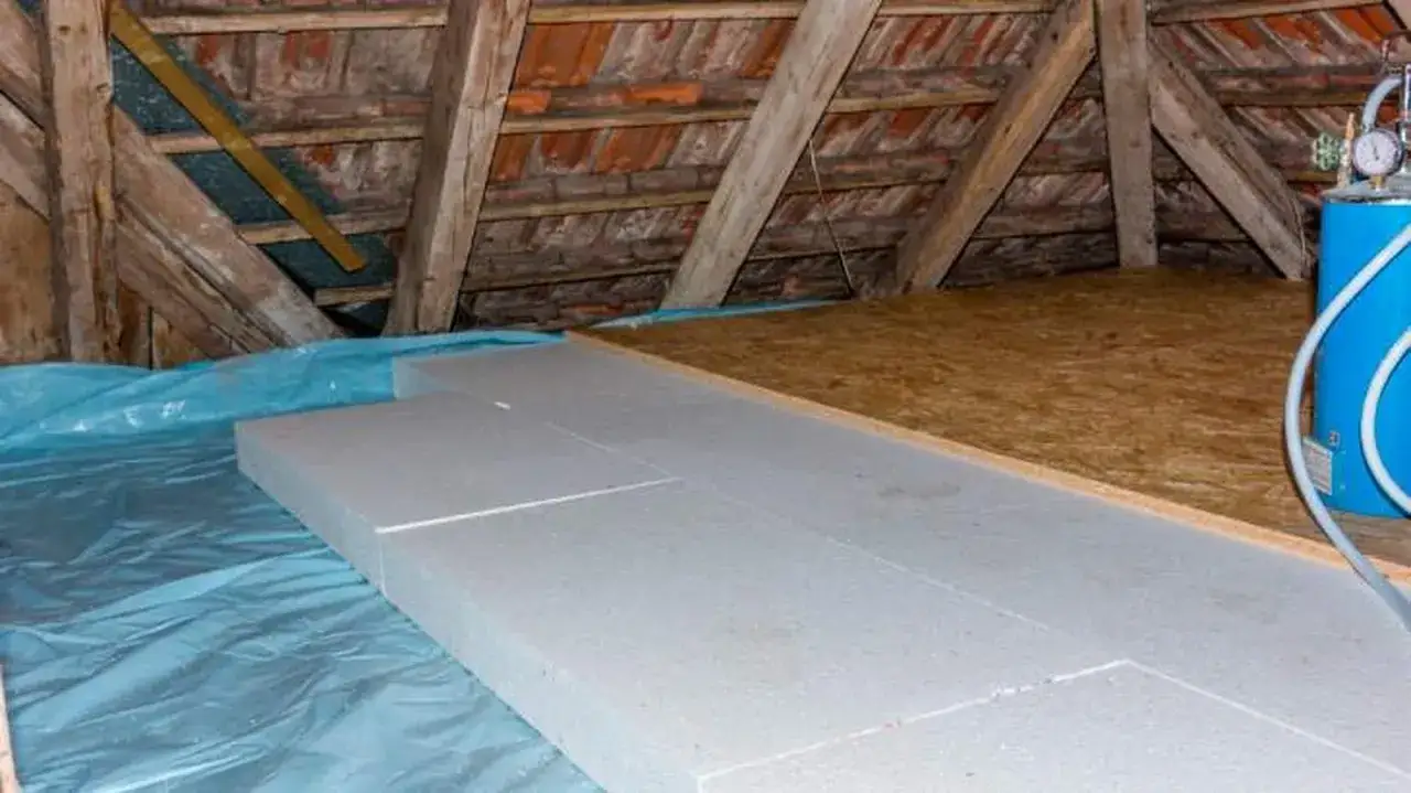 Aislamiento de suelo en una casa antigua, con planchas de poliestireno sobre pl&aacute;stico azul y tablero de OSB.
