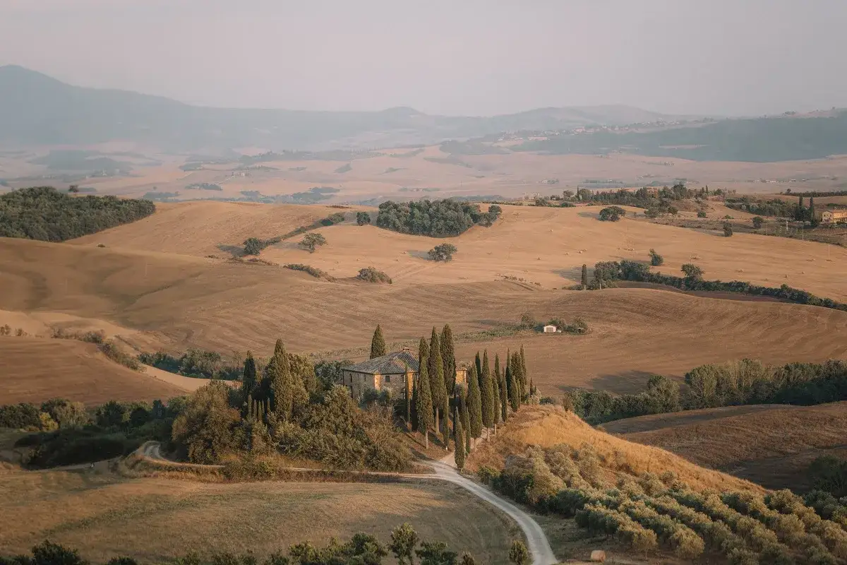 Dolci colline toscane, un casale con cipressi e un sentiero che sembra da dove parte la Via Francigena.