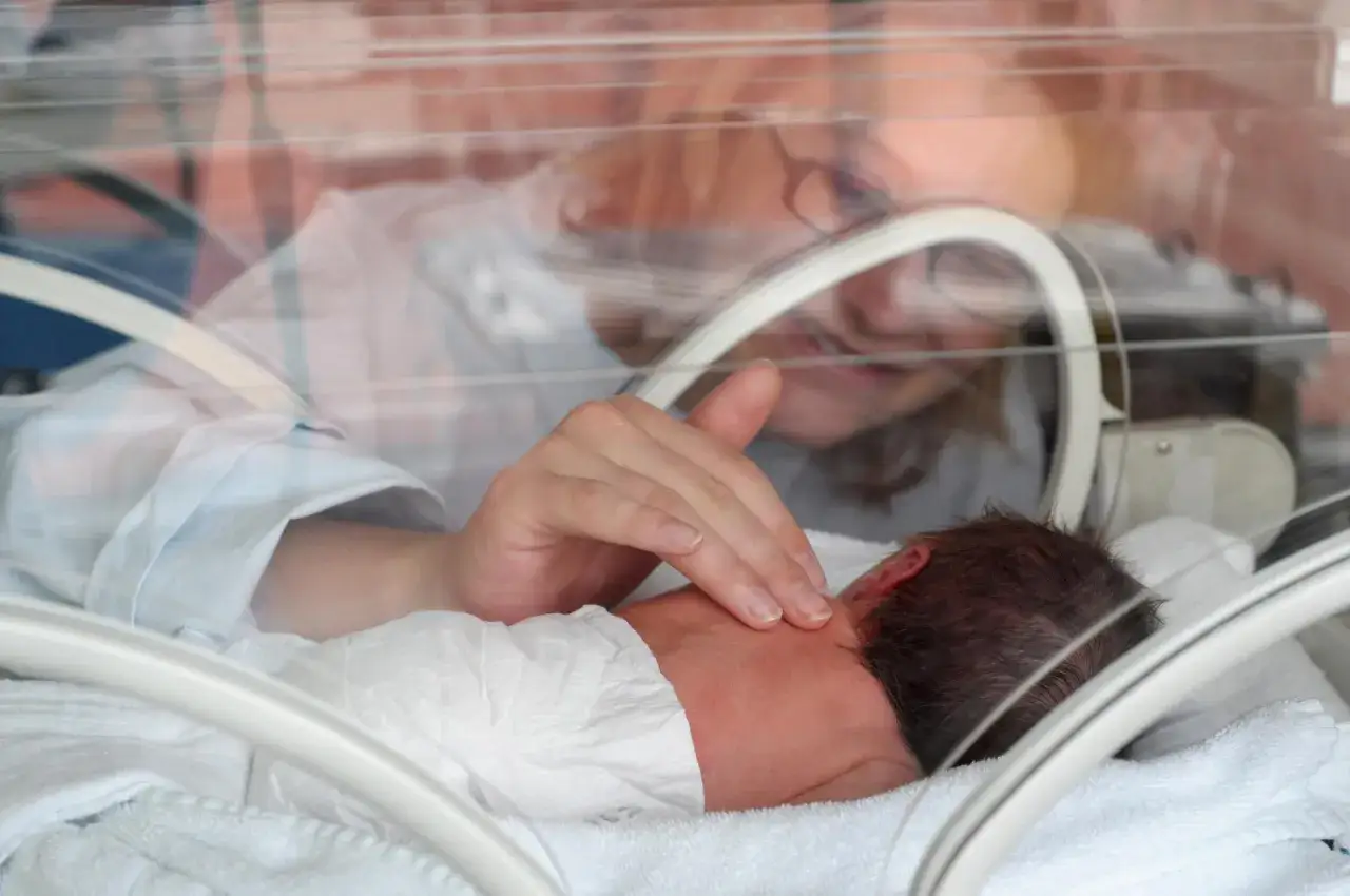 Delikatny dotyk matki dla dziecka urodzonego w 25 tygodniu ciąży. Maluch w inkubatorze czuje miłość.