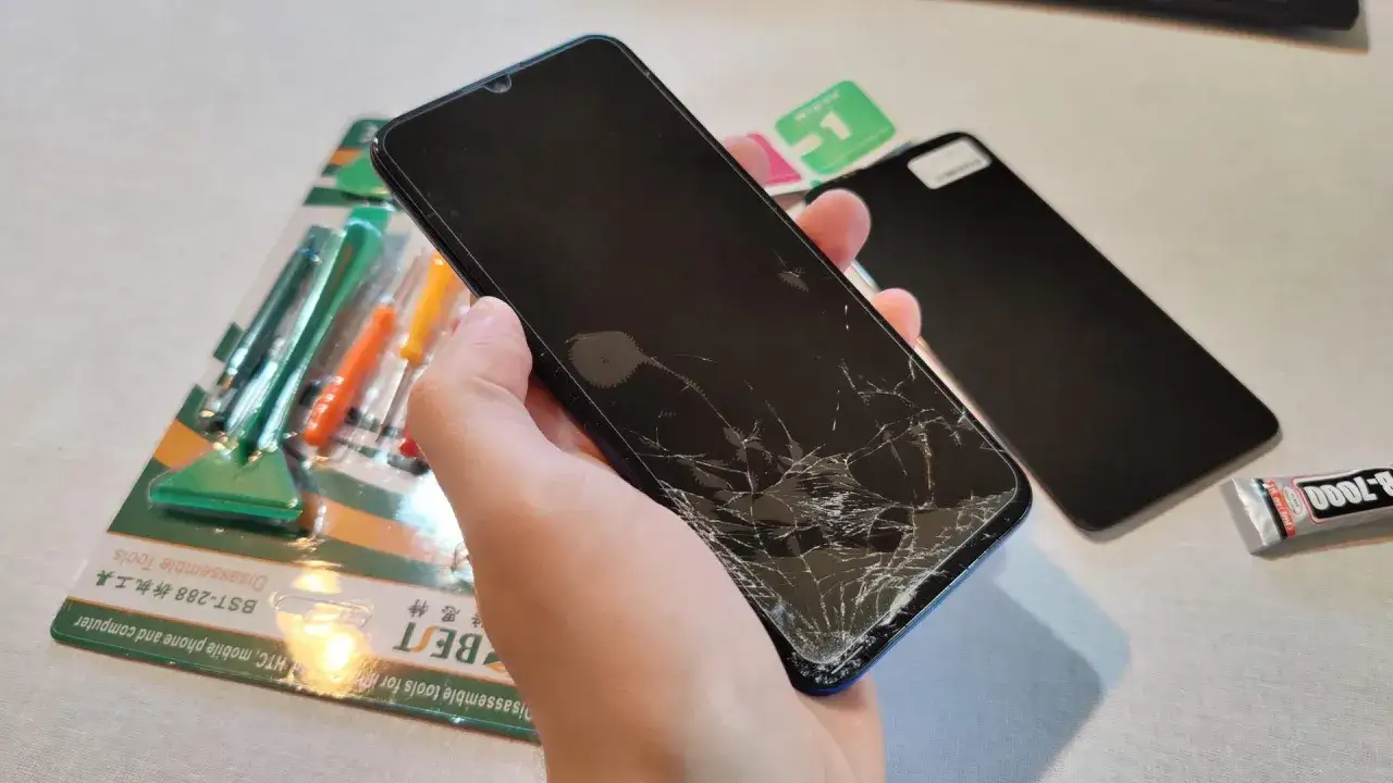 Zepsuta szybka w telefonie czeka na wymianę. Zestaw narzędzi i nowa szybka sugerują, że niedługo dowiesz się, ile trwa wymiana szybki w telefonie.