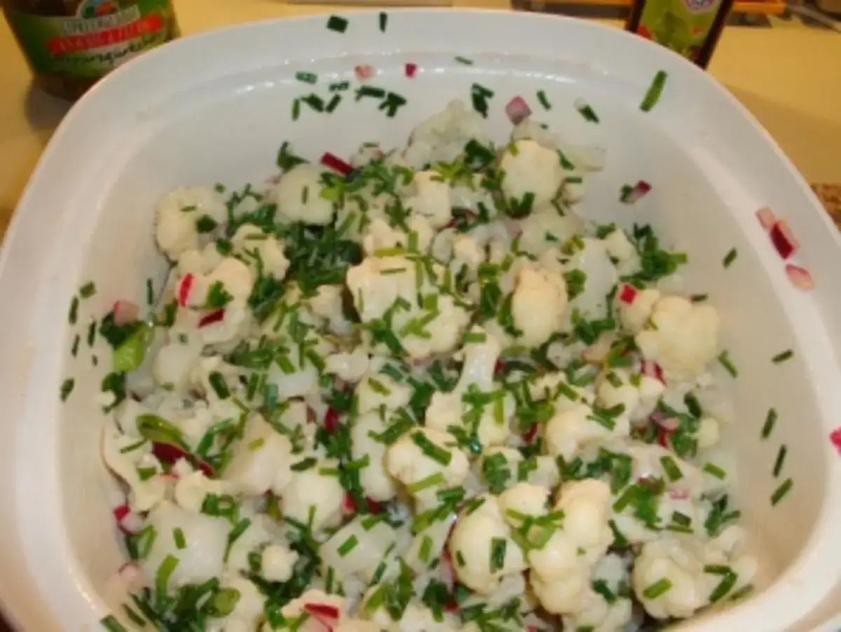 Frischer blumenkohl salat mit Schnittlauch und roten Zwiebeln in einer weißen Schüssel, bereit zum Servieren.