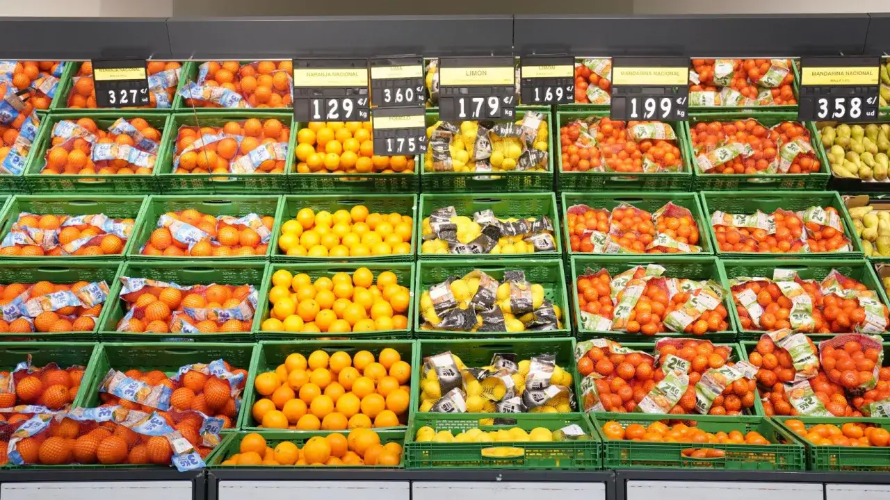 Estanterías llenas de naranjas, limones y mandarinas, todas frutas de temporada, listas para ser compradas.