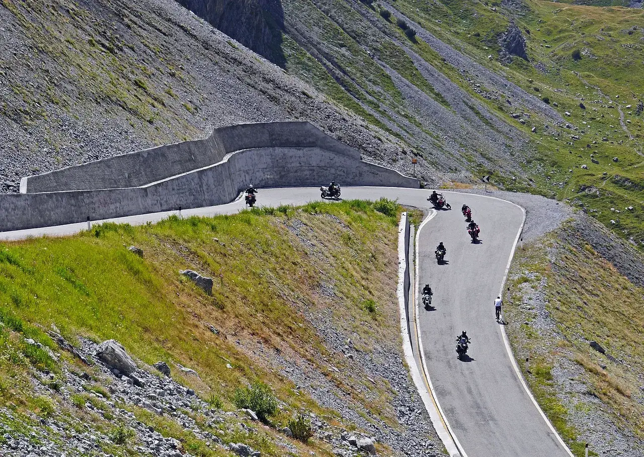 Motocykliści pokonują serpentyny słynnej trasy 100 zakrętów, pnąc się po zboczu góry.
