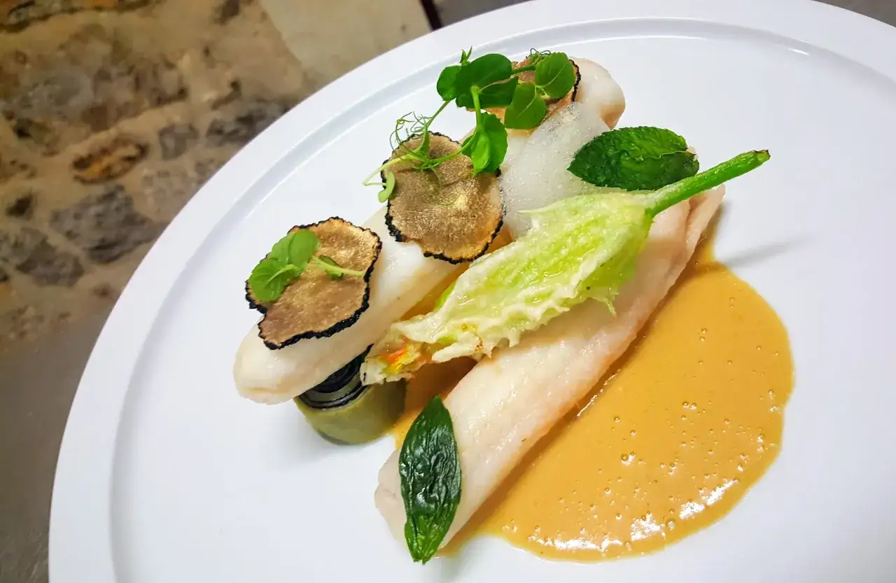 Poisson blanc délicat, truffes noires et fleur de courgette en tempura, nappé d'une sauce onctueuse au beurre nantais.