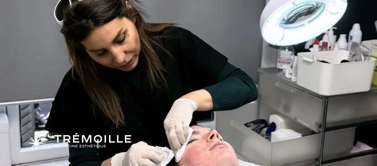 Un soin visage point noir en institut : une esth&eacute;ticienne applique un traitement sur la peau d'une cliente sous une lampe.