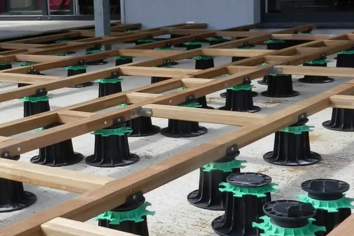 Structure en bois pour pose lame terrasse sur plots r&eacute;glables noirs et verts.