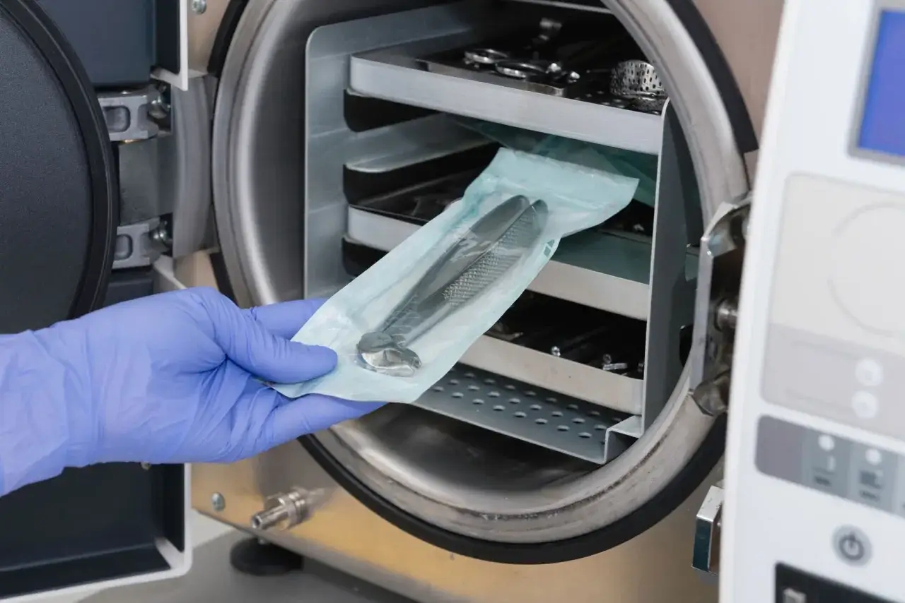 Main tenue, une pince st&eacute;rile est plac&eacute;e dans un autoclave pour la **st&eacute;rilisation eau chaude**.