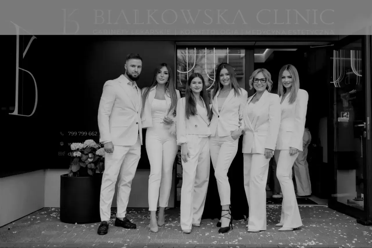 Zespół w białych strojach przed kliniką estetyczną.
