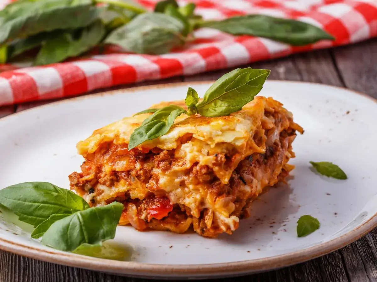 Pyszna lasagne z mięsem i sosem pomidorowym, udekorowana bazylią. Idealna na obiad, gdy szukasz czegoś co zamiast wina do lasagne.