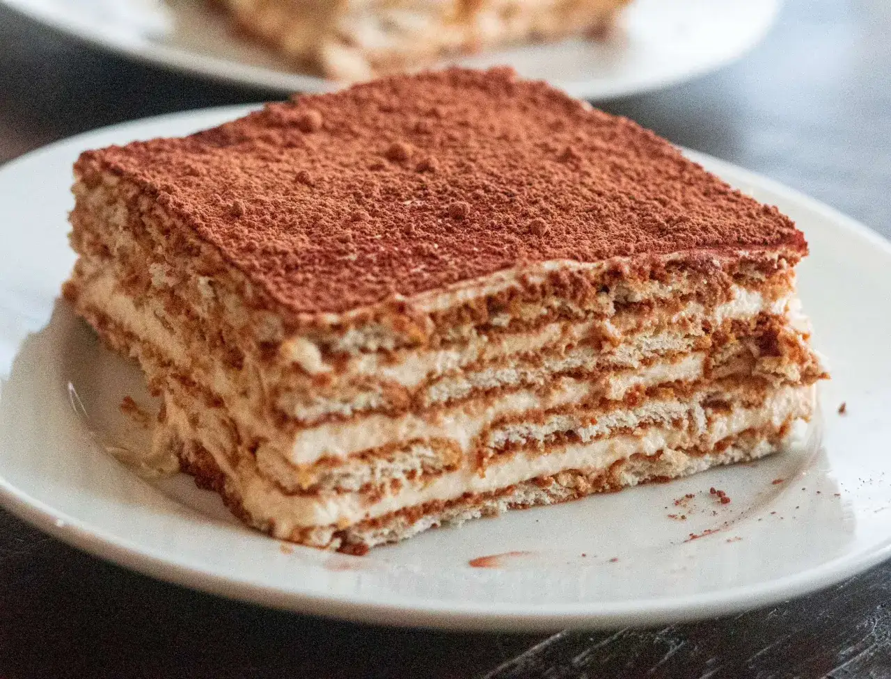 Deliciosa tarta de galletas y café, con capas de crema y espolvoreada con cacao. Un postre perfecto para disfrutar en cualquier momento.