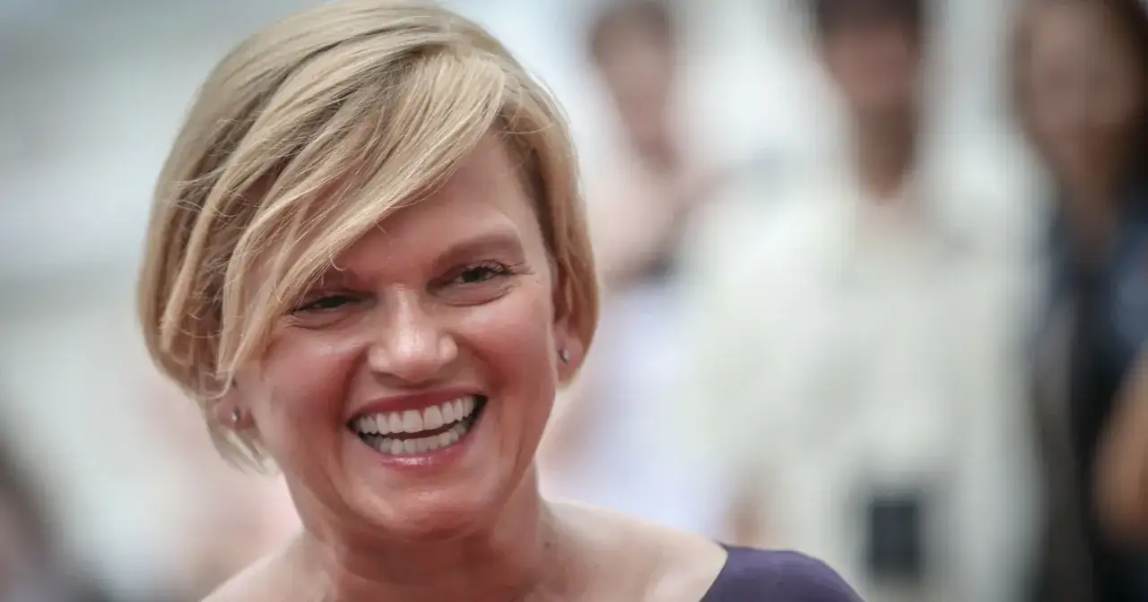 Uśmiechnięta Katarzyna Figura, znana z wielu polskich filmów, z blond włosami i w ciemnej sukience.
