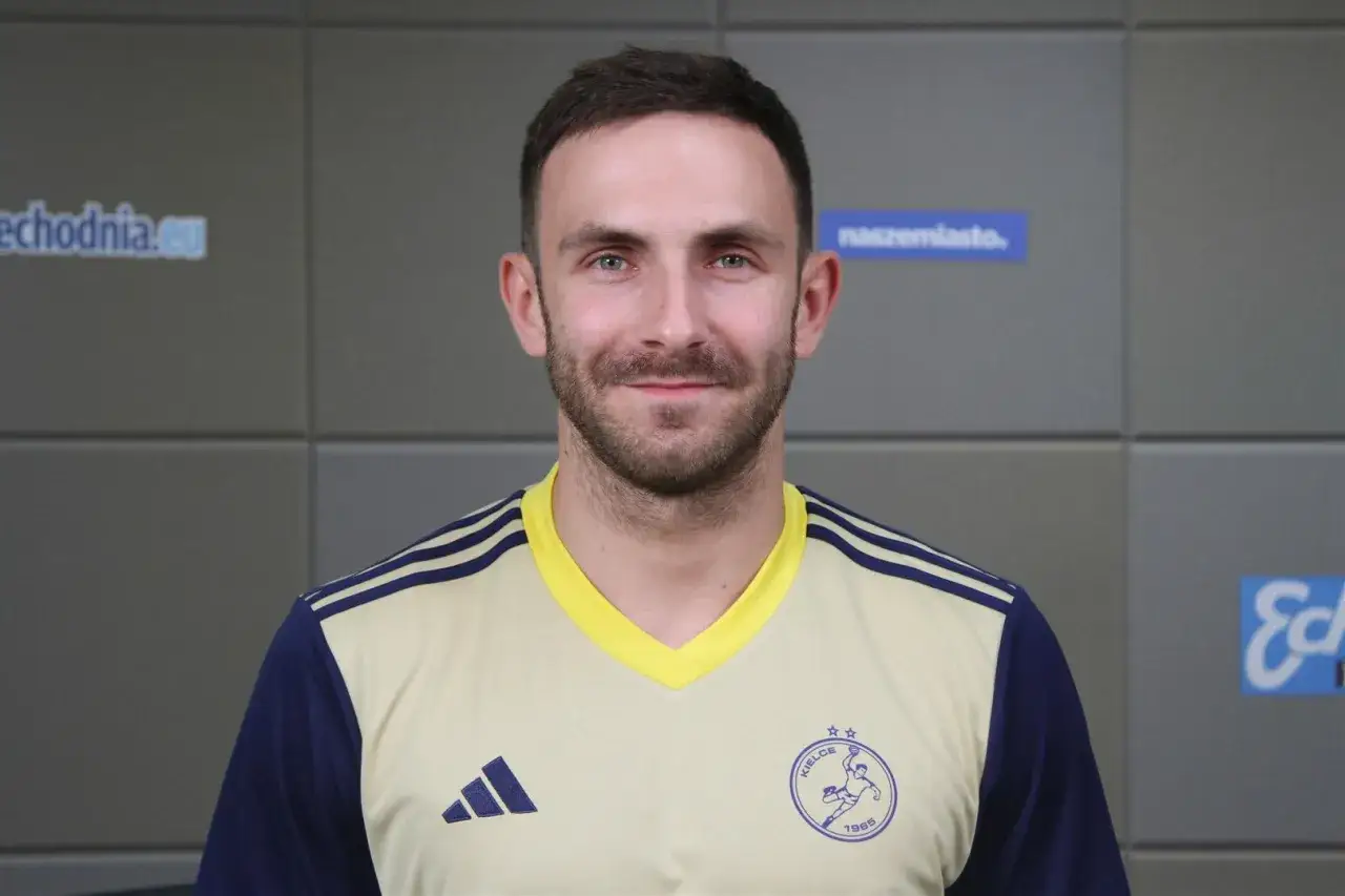 Uśmiechnięty Arkadiusz Moryto w żółto-granatowej koszulce sportowej z herbem klubu.