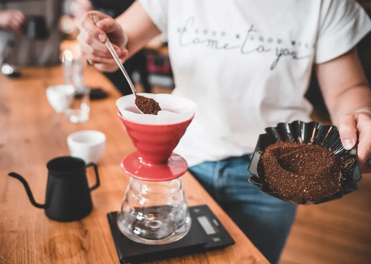 Zubereitung von Filterkaffee: Kaffeepulver wird in einen roten Filterhalter gegeben. So entsteht aromatischer Filterkaffee.