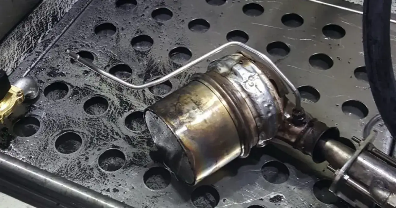 Mokry dpf po czyszczeniu, z widocznymi śladami osadów i wilgoci na metalowej powierzchni.
