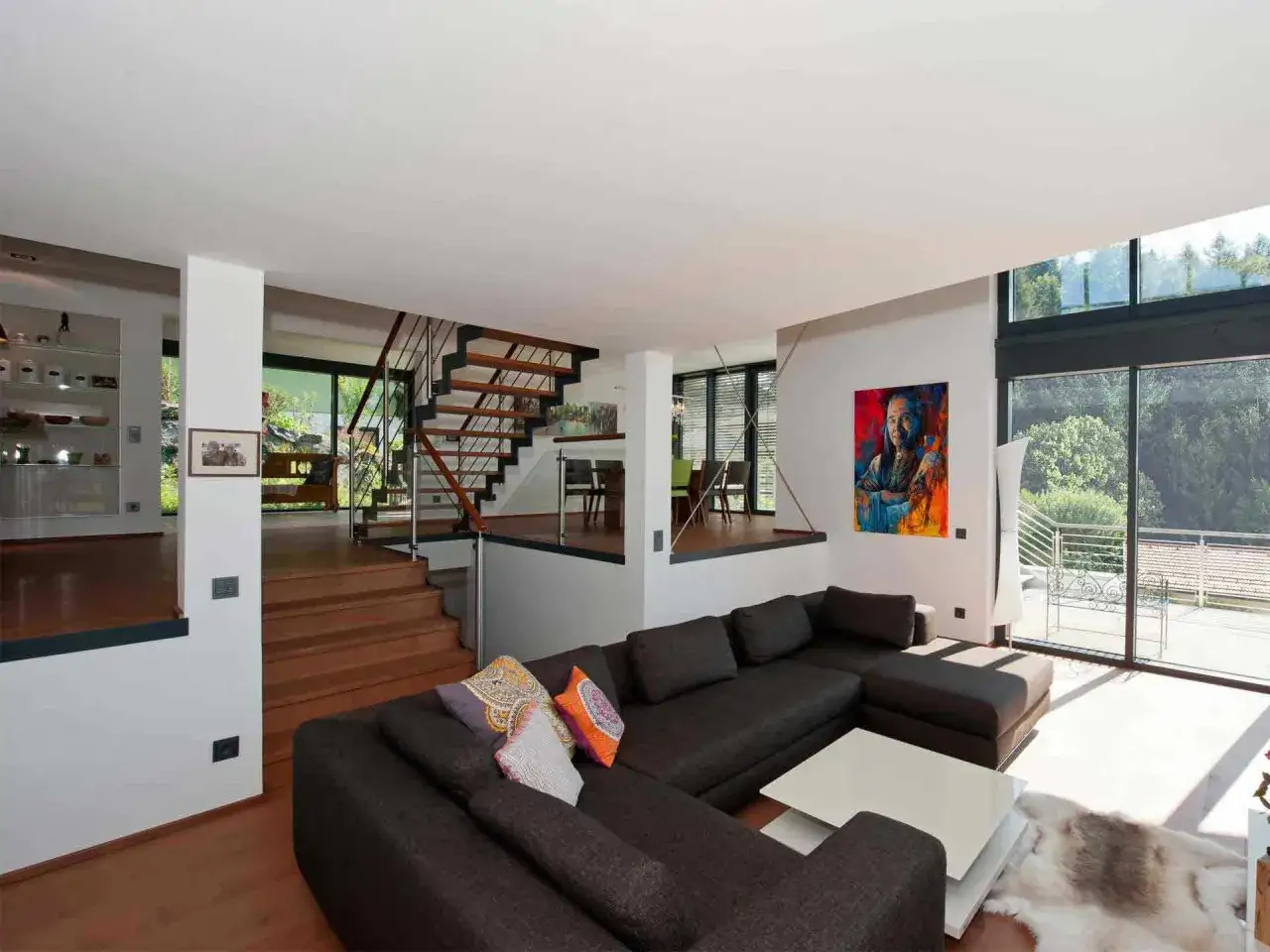 Modernes split level haus mit offener Treppe, gro&szlig;em Sofa und Kunstwerk.