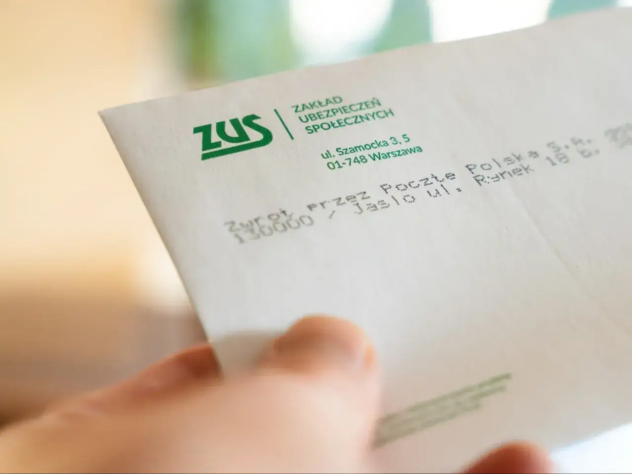 Dłoń trzyma dokument ZUS. Chcesz wiedzieć, gdzie sprawdzić przepracowane lata pracy? ZUS to miejsce, gdzie uzyskasz takie informacje.