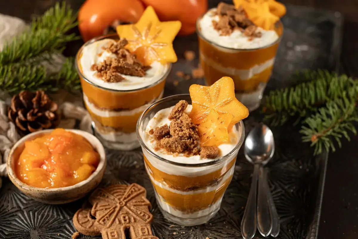 Schichtdessert mit Kaki, Sahne und Keksbröseln, garniert mit Sternfrucht. Ein festliches Kaki-Dessert.