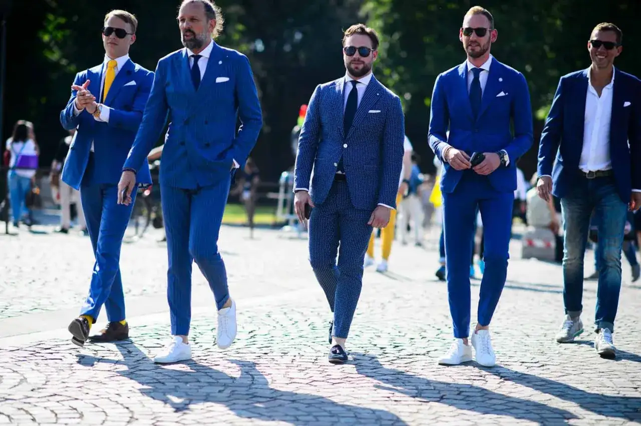 Eleganccy mężczyźni w niebieskich garniturach. Ż&oacute;łty krawat i brązowe buty to świetny przykład, jaki kolor pasuje do niebieskiego.