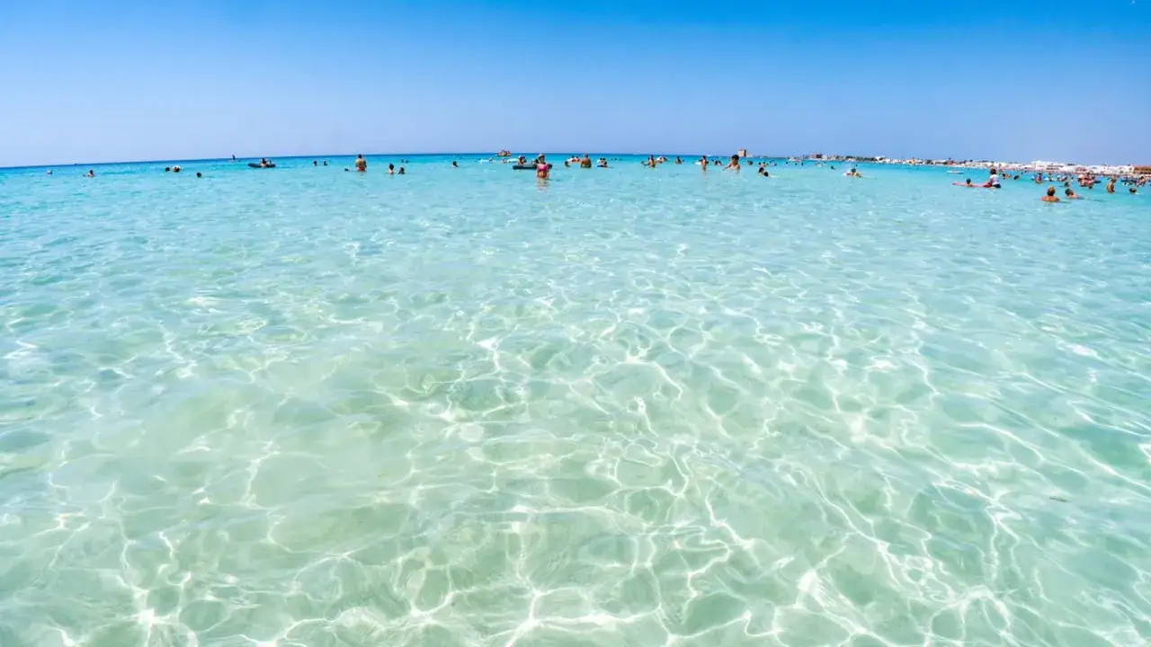 Acque cristalline e turchesi a Marina di Lecce, con bagnanti che si godono il sole e il mare limpido.