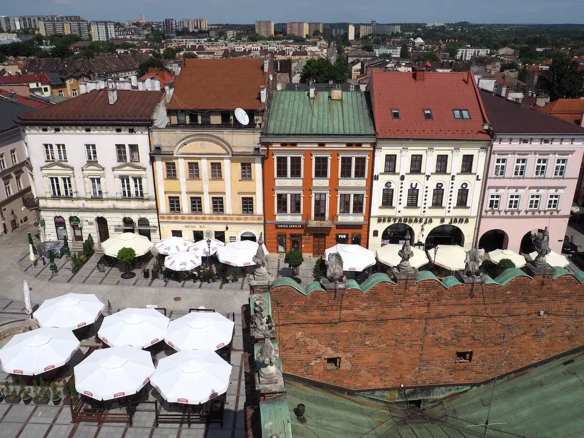 Widok z wieży widokowej w Tarnowie na kolorowe kamienice Rynku i białe parasole kawiarniane.