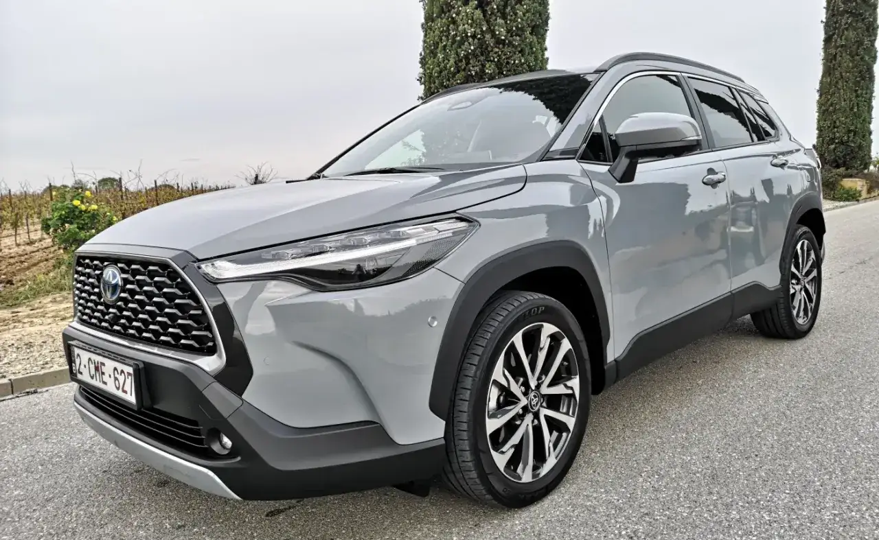 Szary Toyota Kluger na tle winnicy i drzew. Nowoczesny SUV z hybrydowym napędem.