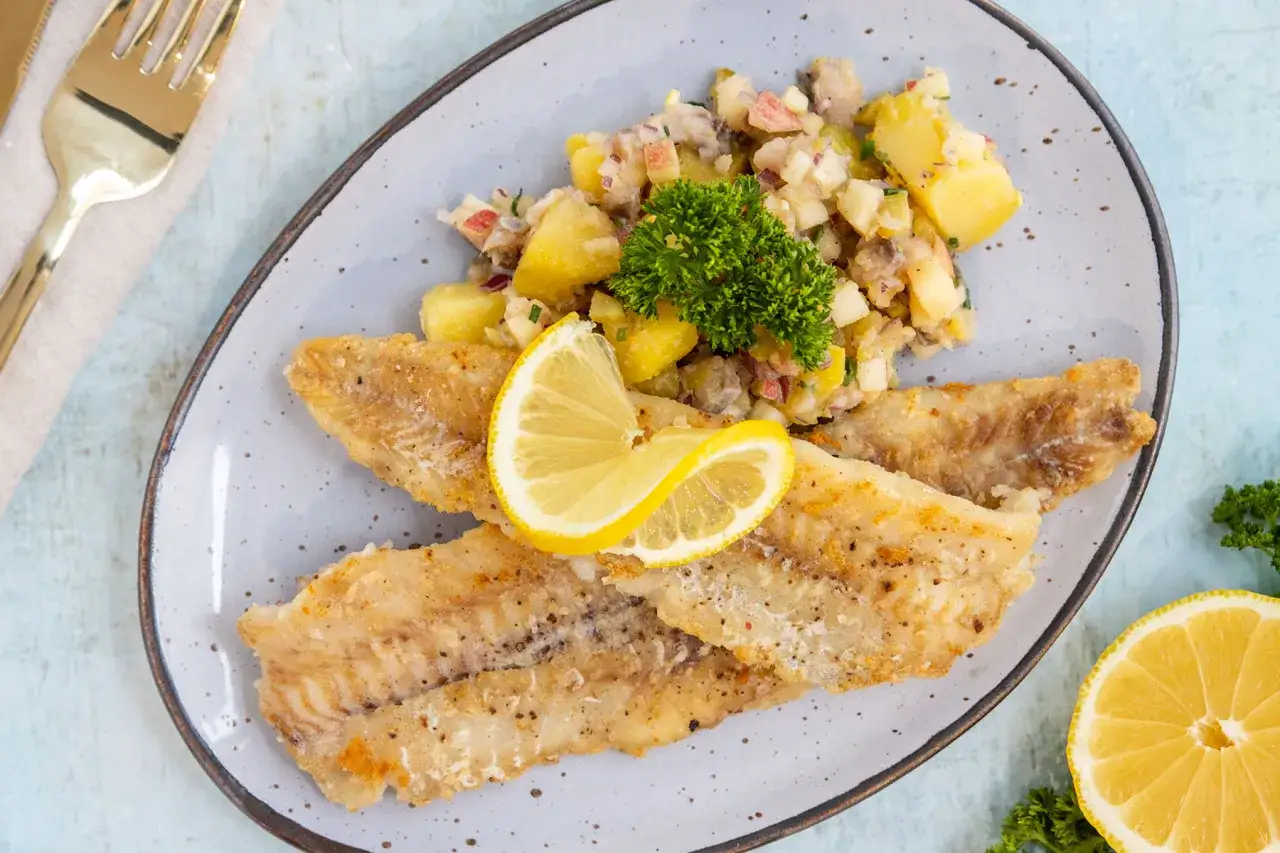 Gebratene Seelachsfilets mit Kartoffel-Apfel-Salat, garniert mit Zitrone und Petersilie. Perfekt für schnelle Seelachsfilet Rezepte Pfanne.