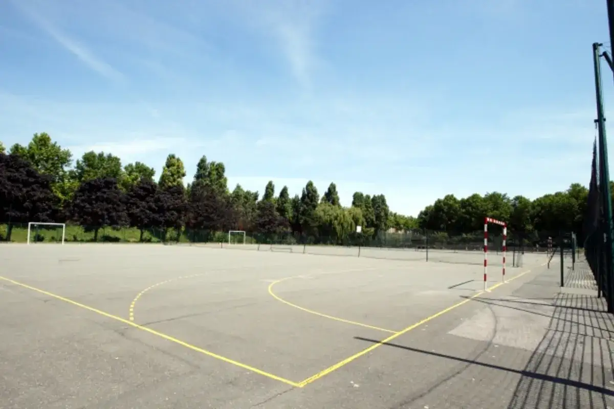 Terrain de sport extérieur avec des buts de football et de handball, idéal pour une partie de five Paris 18.