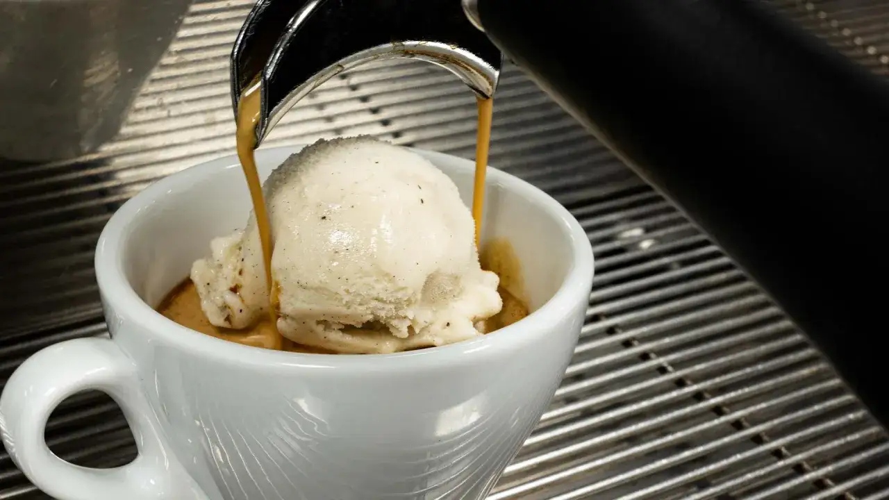 Heißer Espresso fließt über eine Kugel Vanilleeis in einer weißen Tasse. Ein perfektes cafe mit eis.