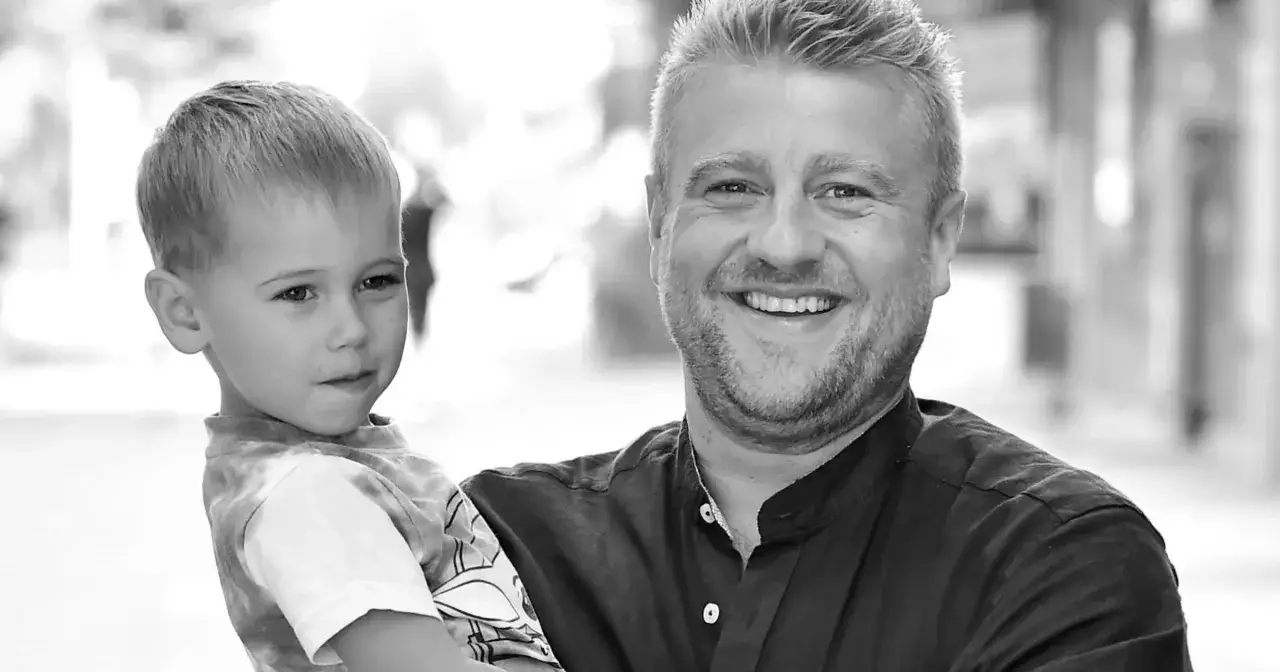 Tomasz Jakubiak z uśmiechem trzyma na rękach małe dzieci.