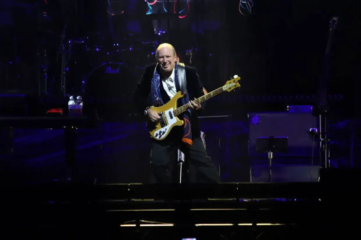 Muzyk gra na gitarze basowej podczas koncertu. To mógłby być sam Hans Zimmer w Krakowie, tworzący magiczną atmosferę.