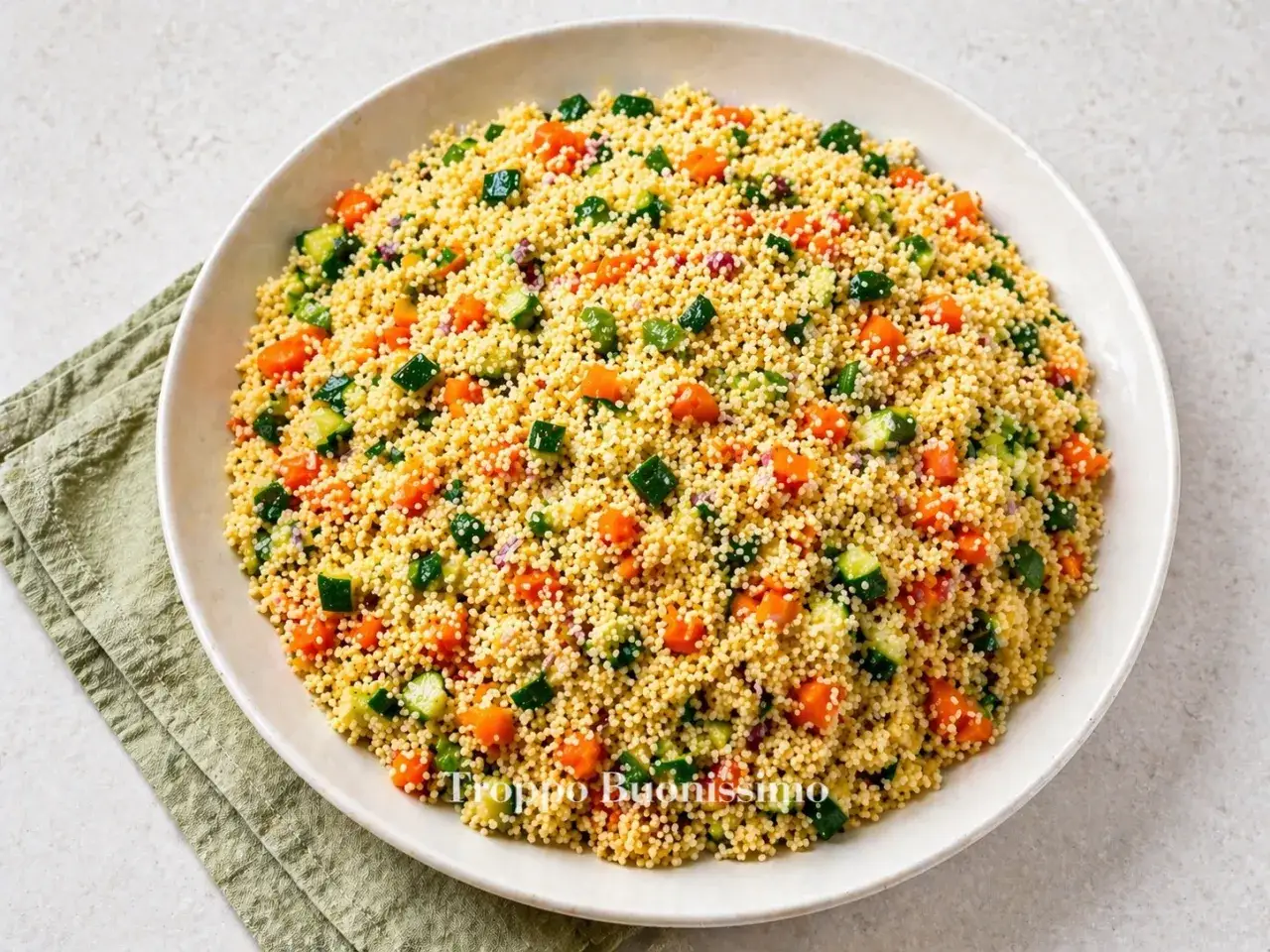 Un piatto invitante di cous cous con carote, zucchine e cipolla rossa. Una ricetta fresca e colorata, perfetta per l'estate.