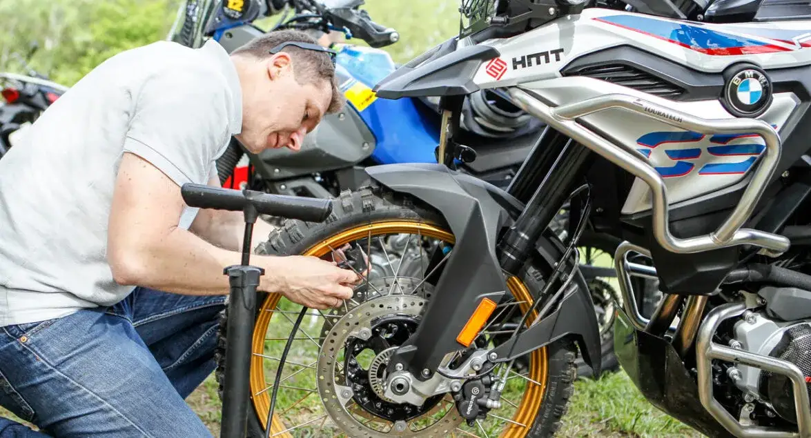 motocyklista zmieniający oponę w terenie