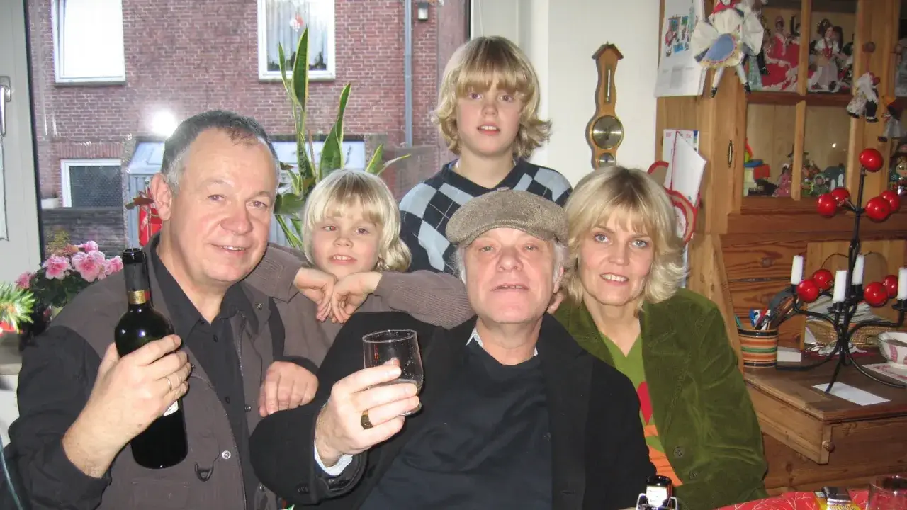 Familjefoto med en man som håller en vinflaska, en kvinna och två barn. Kanske kim larsen barn?