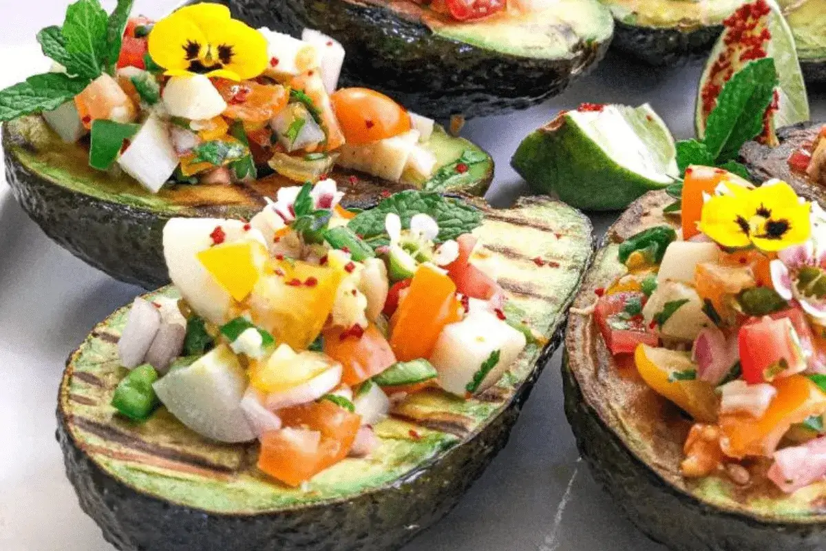 Gegrillte Avocados gef&uuml;llt mit einem bunten Salsa-Mix &ndash; eine k&ouml;stliche Idee f&uuml;r Avocado Rezepte Hauptgericht, garniert mit essbaren Bl&uuml;ten.