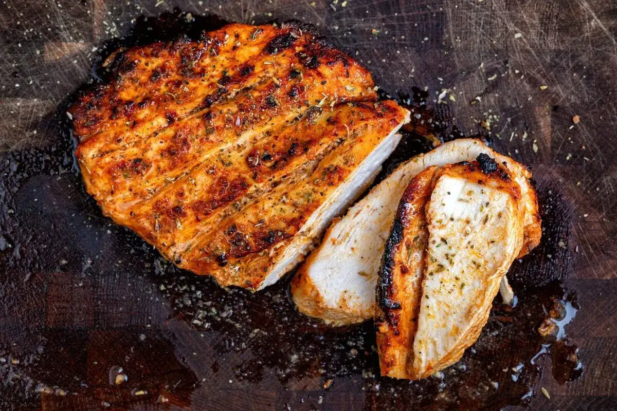 Soczysty piers z kurczaka air fryer, idealnie przypieczony, pokrojony na plastry, leży na drewnianej desce.