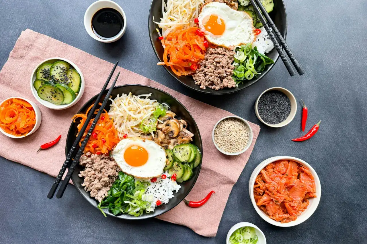 Dwa miski z Bibimbap przepis, z ryżem, mielonym mięsem, jajkiem sadzonym, warzywami i kimchi.